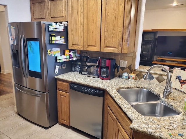 kitchen with sink, light tile patterned floors, appliances with stainless steel finishes, light stone countertops, and decorative backsplash