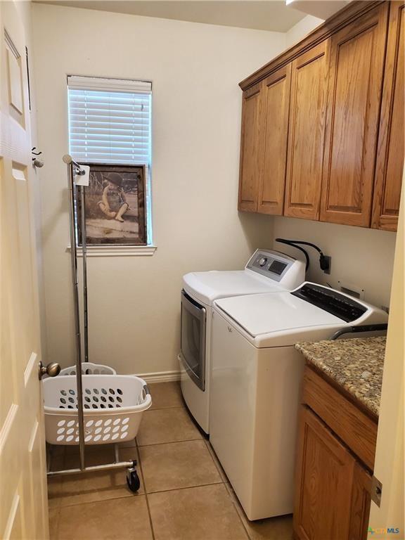 laundry area featuring cabinets, light tile patterned flooring, and washing machine and clothes dryer