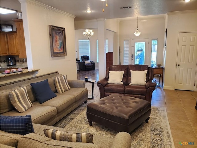 living room with a notable chandelier, ornamental molding, and light tile patterned floors