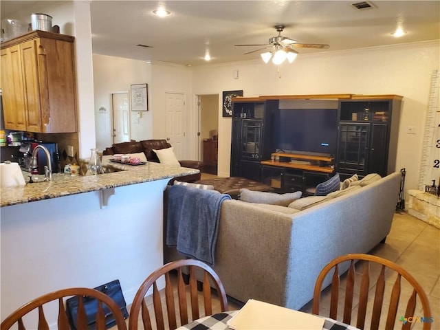 living room with light tile patterned floors, ornamental molding, and ceiling fan