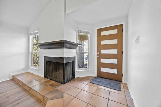 tiled foyer featuring a tiled fireplace and vaulted ceiling