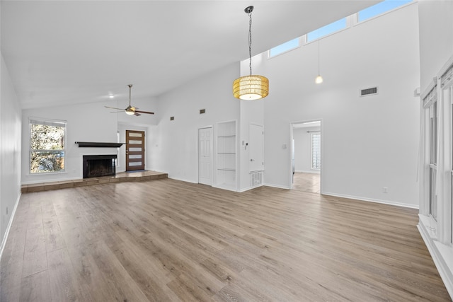 unfurnished living room with plenty of natural light, high vaulted ceiling, light hardwood / wood-style floors, and ceiling fan