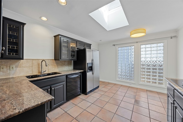 kitchen featuring light tile patterned flooring, tasteful backsplash, dishwasher, sink, and stainless steel fridge