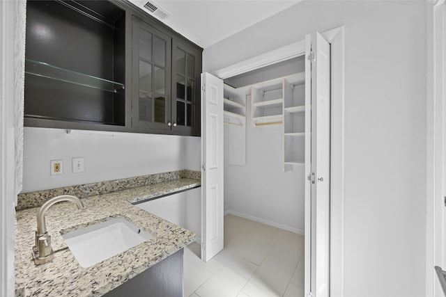 kitchen featuring light stone counters, sink, and light tile patterned flooring