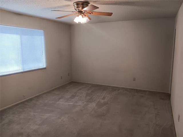 unfurnished room with ceiling fan, dark carpet, and a textured ceiling