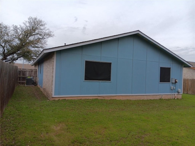 view of side of property with central AC and a lawn