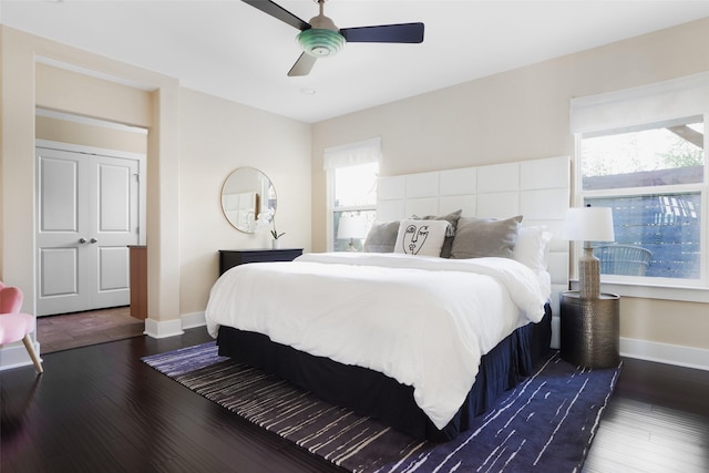 bedroom featuring multiple windows, dark wood-type flooring, and ceiling fan