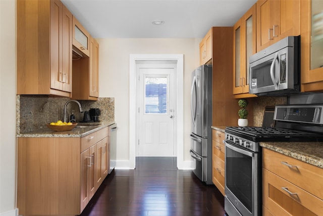 kitchen with tasteful backsplash, stainless steel appliances, sink, and stone counters