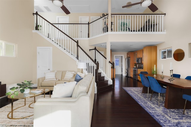 living room featuring ceiling fan, a towering ceiling, and dark hardwood / wood-style flooring