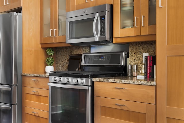 kitchen featuring stainless steel appliances, light stone countertops, and backsplash