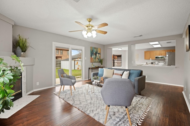 living room with ceiling fan, dark wood-type flooring, a textured ceiling, and a high end fireplace