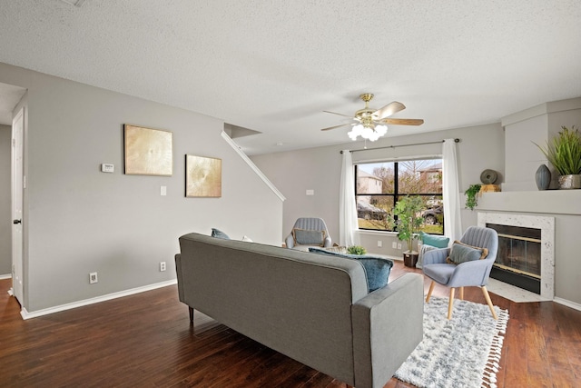 living room featuring dark wood-type flooring, ceiling fan, a high end fireplace, and a textured ceiling