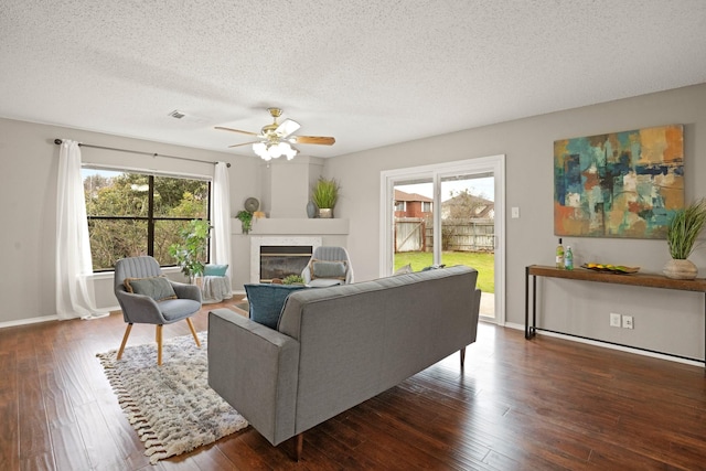 living room featuring ceiling fan, dark hardwood / wood-style floors, a textured ceiling, and a wealth of natural light