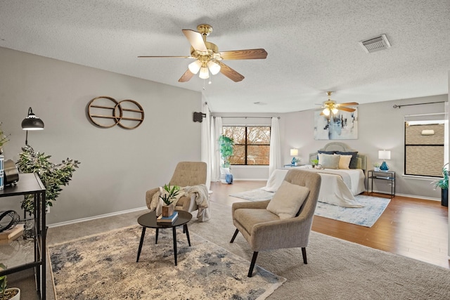 bedroom with ceiling fan, hardwood / wood-style flooring, and a textured ceiling