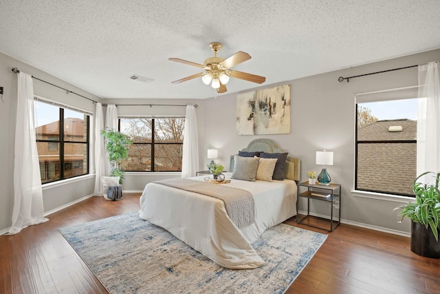 bedroom featuring dark wood-type flooring, a textured ceiling, and ceiling fan