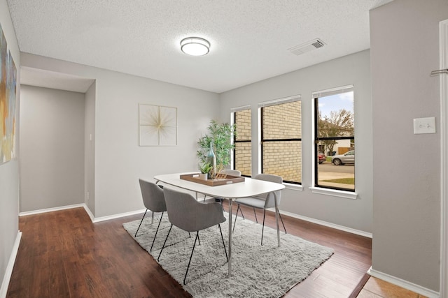 dining space featuring dark wood-type flooring, a textured ceiling, and a wealth of natural light