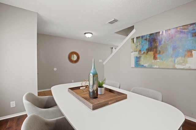 dining room featuring dark wood-type flooring and a textured ceiling