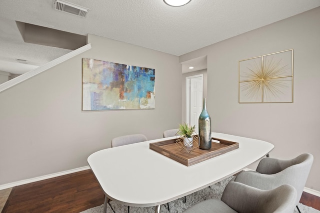 dining space with wood-type flooring and a textured ceiling