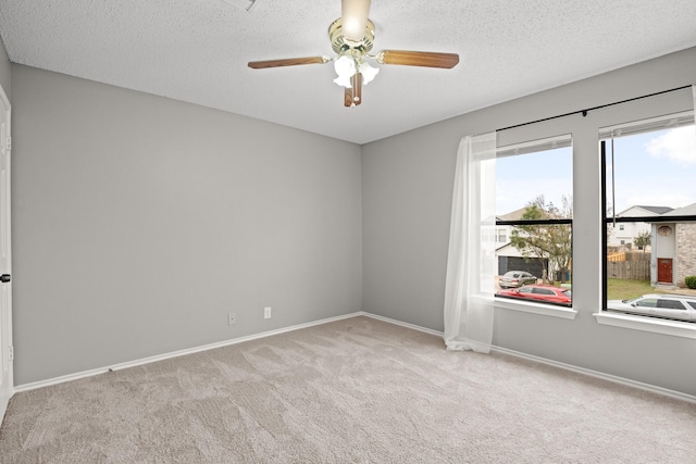 unfurnished room featuring ceiling fan, light colored carpet, and a textured ceiling