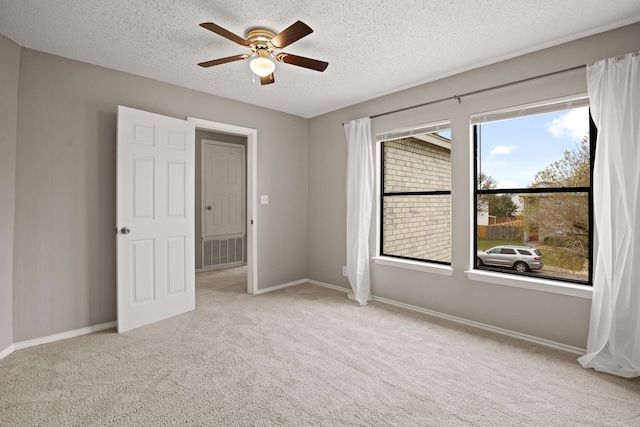 carpeted spare room featuring ceiling fan, plenty of natural light, and a textured ceiling