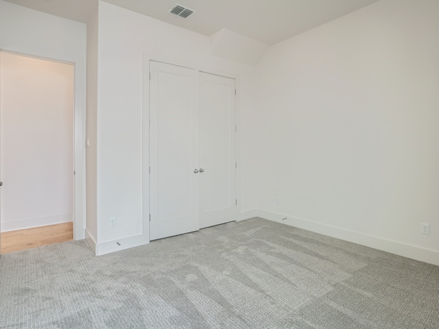 unfurnished bedroom with a closet and light carpet