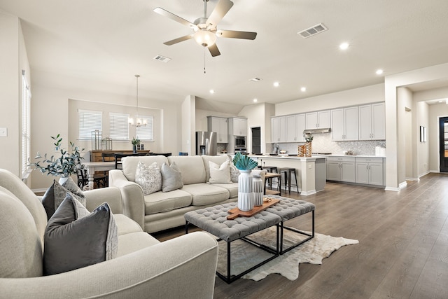 living room featuring ceiling fan with notable chandelier and wood-type flooring