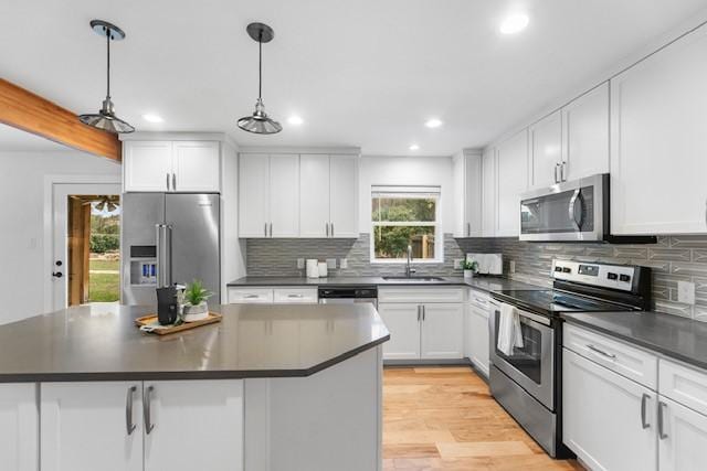 kitchen featuring sink, decorative light fixtures, white cabinets, and appliances with stainless steel finishes