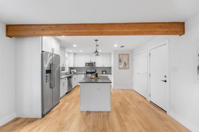 kitchen with appliances with stainless steel finishes, white cabinetry, a center island, tasteful backsplash, and decorative light fixtures