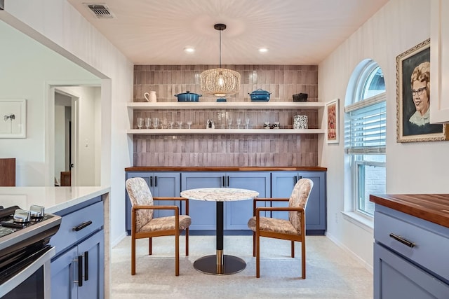 interior space with a healthy amount of sunlight, decorative light fixtures, stainless steel range oven, and backsplash