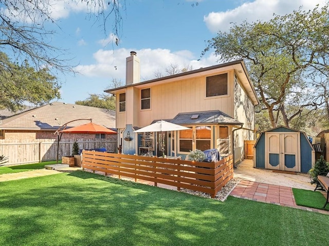 rear view of property with a storage unit, a patio, and a lawn