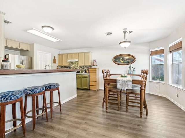 kitchen featuring sink, stainless steel refrigerator, dark hardwood / wood-style flooring, green cabinets, and backsplash