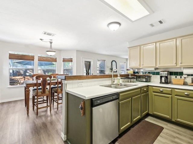 kitchen with sink, green cabinets, hanging light fixtures, stainless steel dishwasher, and kitchen peninsula