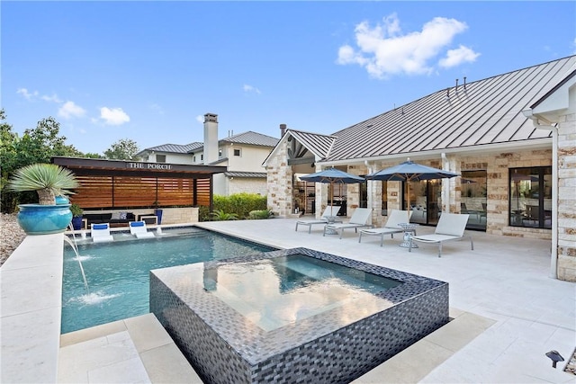 view of pool with an in ground hot tub, pool water feature, and a patio