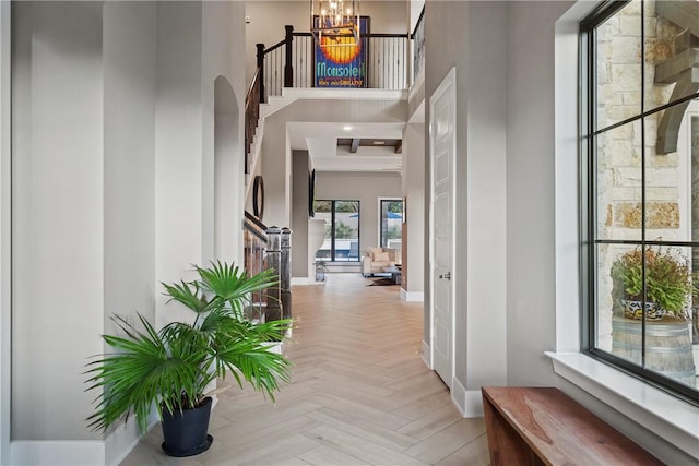 corridor with a high ceiling, light parquet flooring, and a chandelier