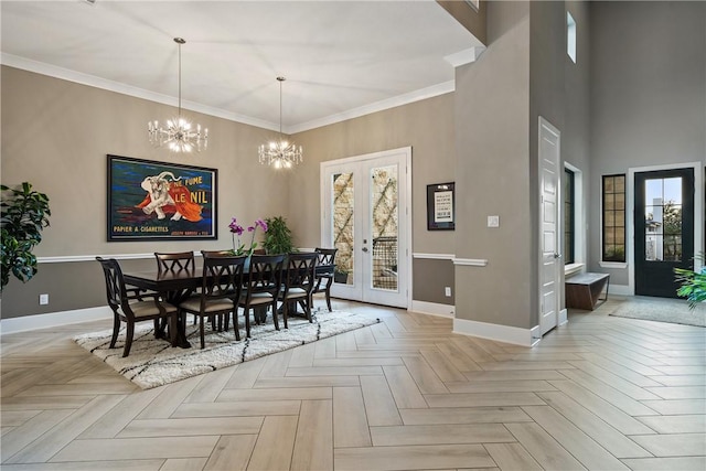 dining area with a towering ceiling, light parquet floors, crown molding, an inviting chandelier, and french doors