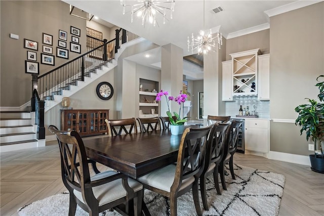 dining room featuring crown molding, indoor bar, a chandelier, and light parquet floors