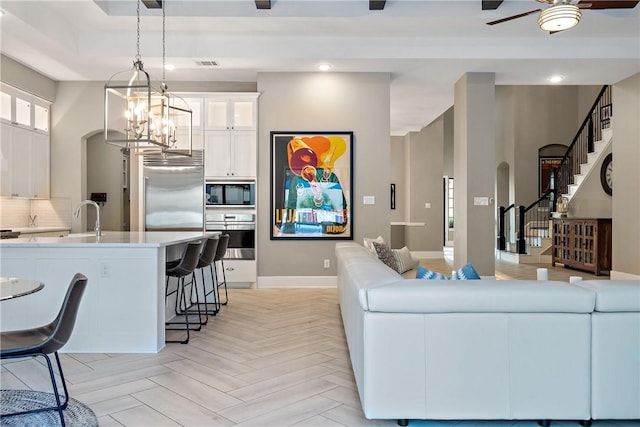 living room with sink, ceiling fan with notable chandelier, and light parquet floors