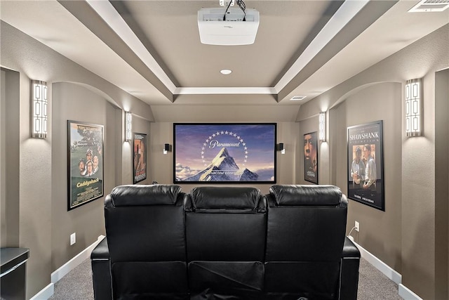 carpeted home theater with a raised ceiling