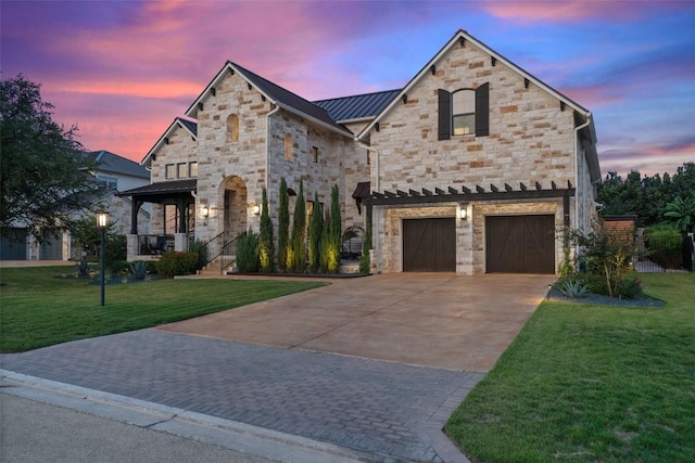 107 Bisset Ct, Austin, TX 78738 - french country home with concrete driveway, stone siding, a standing seam roof, and a yard