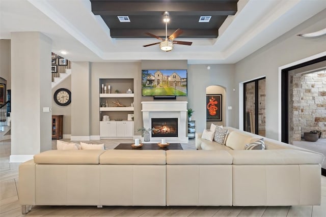 107 Bisset Ct, Austin, TX 78738 - living area featuring a glass covered fireplace, ceiling fan, visible vents, built in shelves, and stairway
