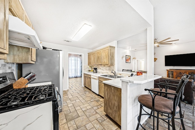 kitchen featuring sink, a breakfast bar area, dishwasher, stainless steel range with gas stovetop, and kitchen peninsula