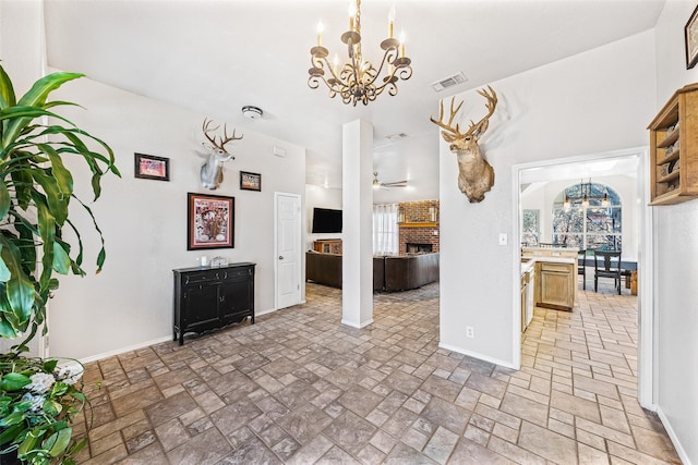 kitchen featuring a brick fireplace and ceiling fan with notable chandelier