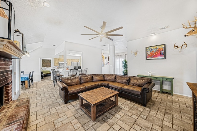 living room with ceiling fan, vaulted ceiling, and a textured ceiling