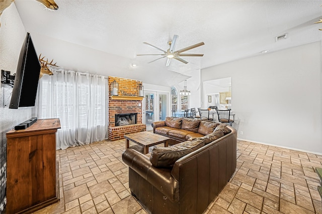 living room featuring ceiling fan, a fireplace, vaulted ceiling, and a textured ceiling