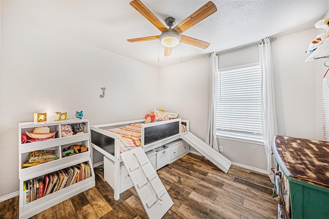 bedroom with ceiling fan, dark hardwood / wood-style flooring, and a textured ceiling