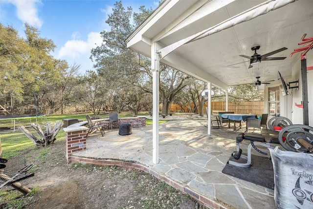 view of patio with ceiling fan, a fire pit, and a trampoline