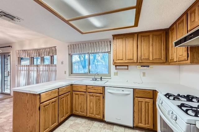 kitchen featuring sink, a textured ceiling, white appliances, and kitchen peninsula