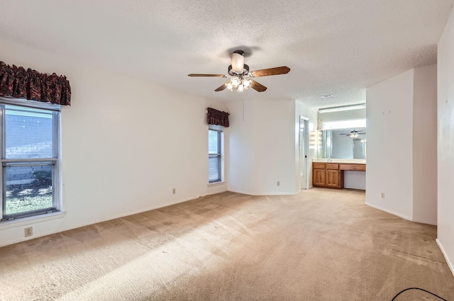 carpeted spare room featuring ceiling fan, built in desk, and a textured ceiling