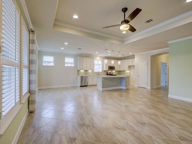 kitchen with ornamental molding, appliances with stainless steel finishes, a center island, and white cabinets