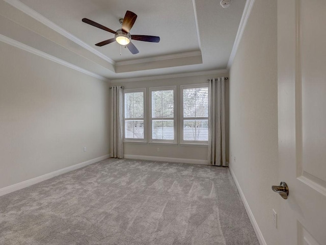 spare room featuring ceiling fan, light colored carpet, ornamental molding, and a raised ceiling